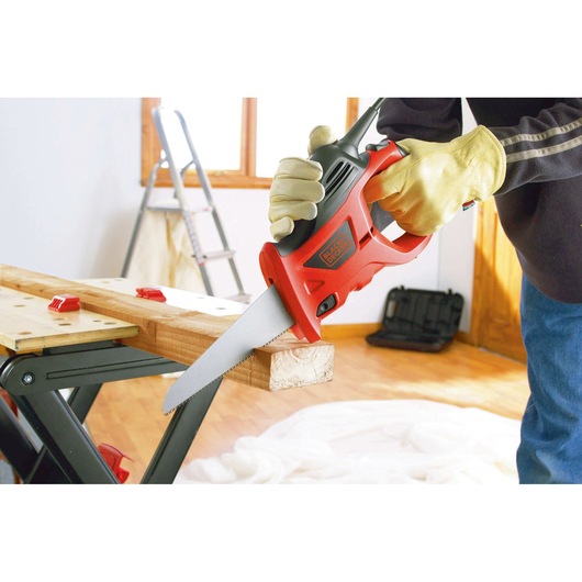 BLACKDECKER KS880EC electric saw cutting wood, close side angle, user with gloves in workshop.