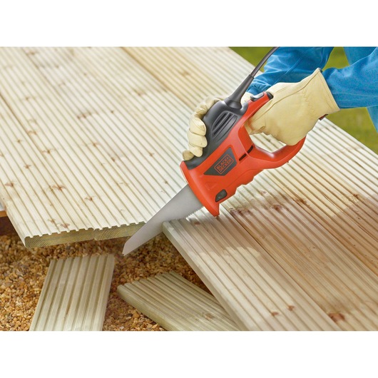 BLACKDECKER KS880EC electric saw cutting wooden planks, closeup with gloved hand outdoors.