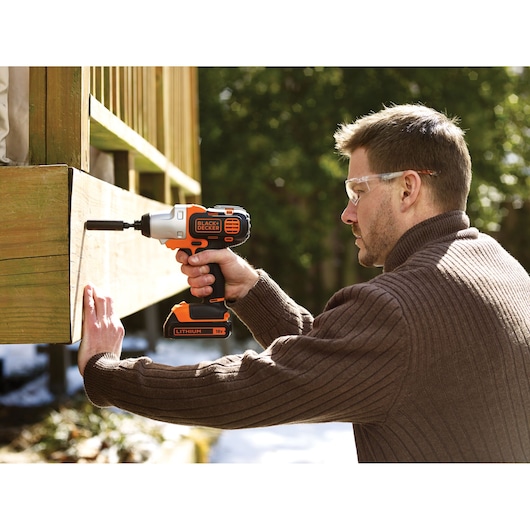 Photo of BLACK+DECKER MTIM3 impact driver used outdoors on wooden structure.