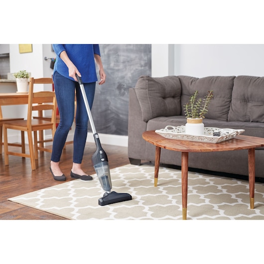BLACKDECKER NSVA315J stick vacuum cleaner in use on patterned rug in living room.