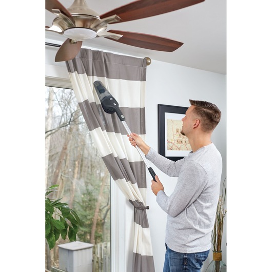 BLACKDECKER NSVA315J handheld vacuum with extension cleaning curtains in living room.