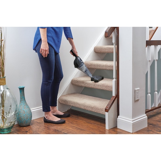 BLACKDECKER NSVA315J handheld vacuum cleaning carpeted stairs in a home setting.
