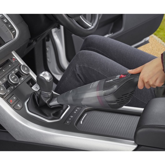 Photo of BLACKDECKER NVB12AVA handheld vacuum cleaning car interior near gearshift.