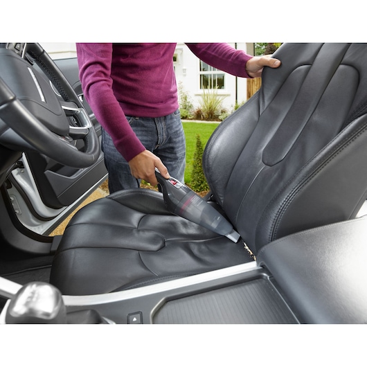 BLACKDECKER NVB12AV handheld vacuum cleaning black leather car seat outdoors.