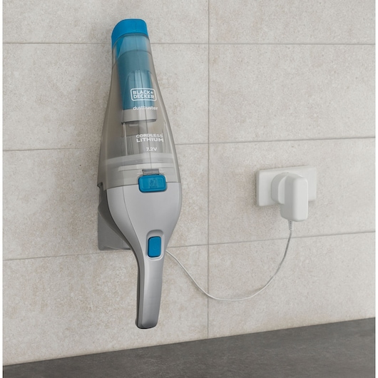 BLACKDECKER NVC215WA cordless handheld vacuum mounted on wall, charging with power adapter, neutral tile background.