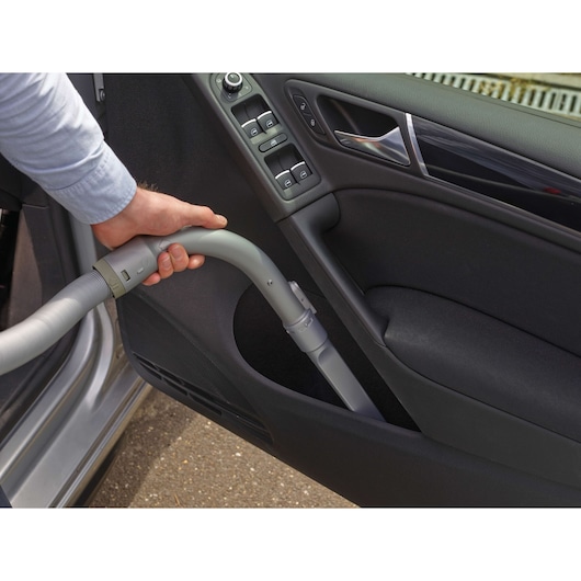 BLACKDECKER PD1200AV car vacuum hose cleaning door interior, close-up of hand holding nozzle.