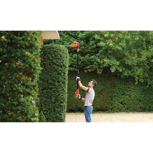 BLACKDECKER PH5551 hedge trimmer used outdoors on tall bushes, showing telescopic pole extension.