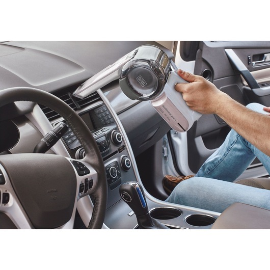 Photo of BLACK+DECKER PV1820LRGP handheld vacuum cleaner being used to clean a car interior dashboard vent.