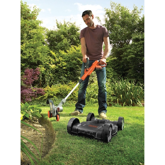 Photo of BLACKDECKER STC1820CM grass trimmer with detachable mower base used in a garden.