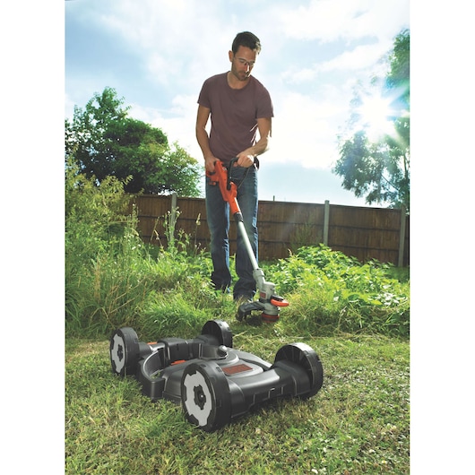 BLACKDECKER STC1820CM grass trimmer and mower photographed in a garden setting.