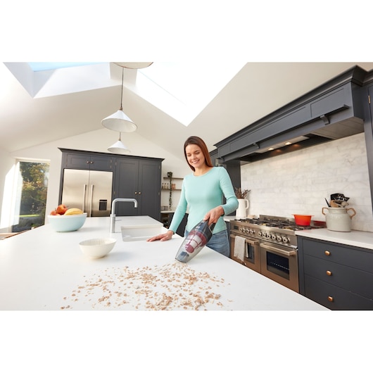 BLACKDECKER SVB620JW handheld vacuum cleaning crumbs on kitchen counter, woman using device in modern kitchen.