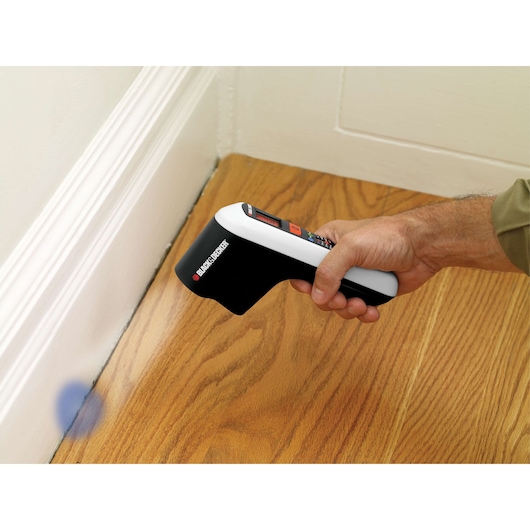 BLACK+DECKER TLD100 thermal leak detector used on wood floor near baseboard.