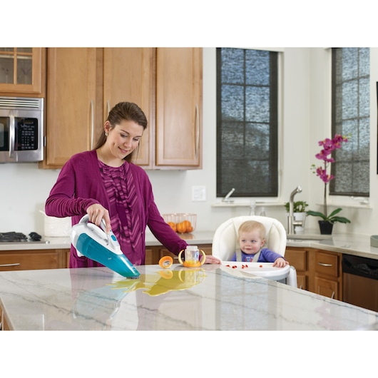 BLACK+DECKER WDA315J handheld vacuum cleaning liquid from a kitchen countertop, baby in high chair in background.