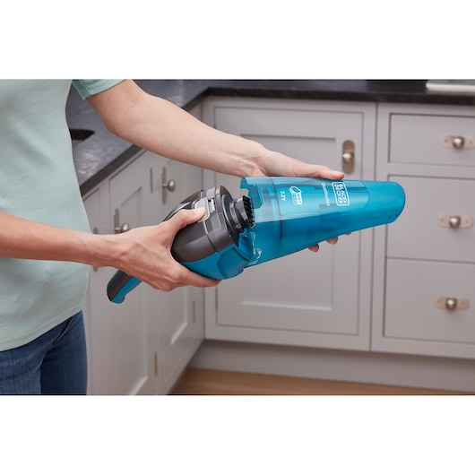 BLACKDECKER WDC215WA handheld vacuum in blue being opened in a kitchen setting.